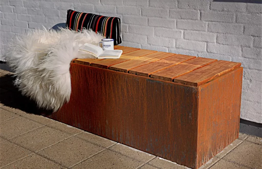 Rustik bænk med pude, bog og kop udenfor