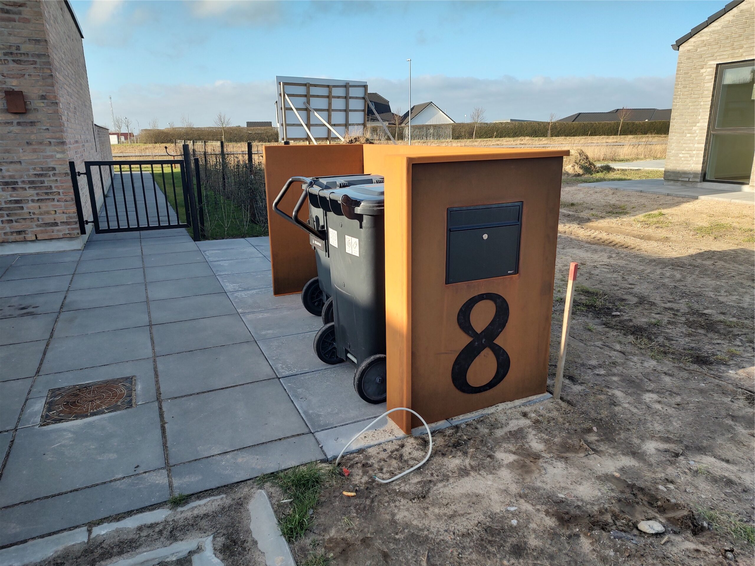 Moderne postkasse og affaldsbeholdere foran hus nummer otte