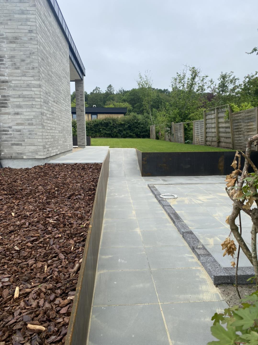 Moderne have med flisebelægning og græsplæne