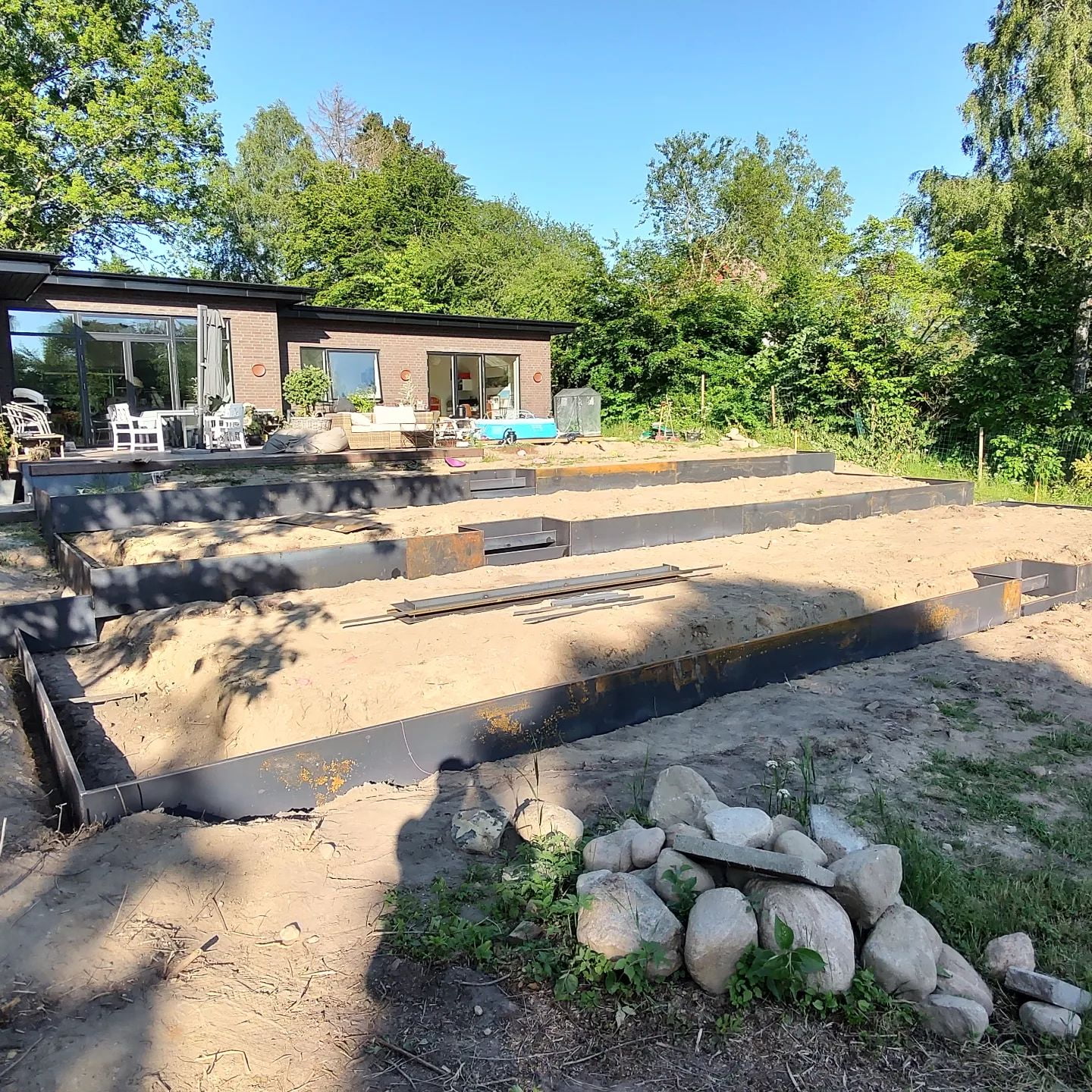 Haveprojekt med hævede bede foran moderne hus