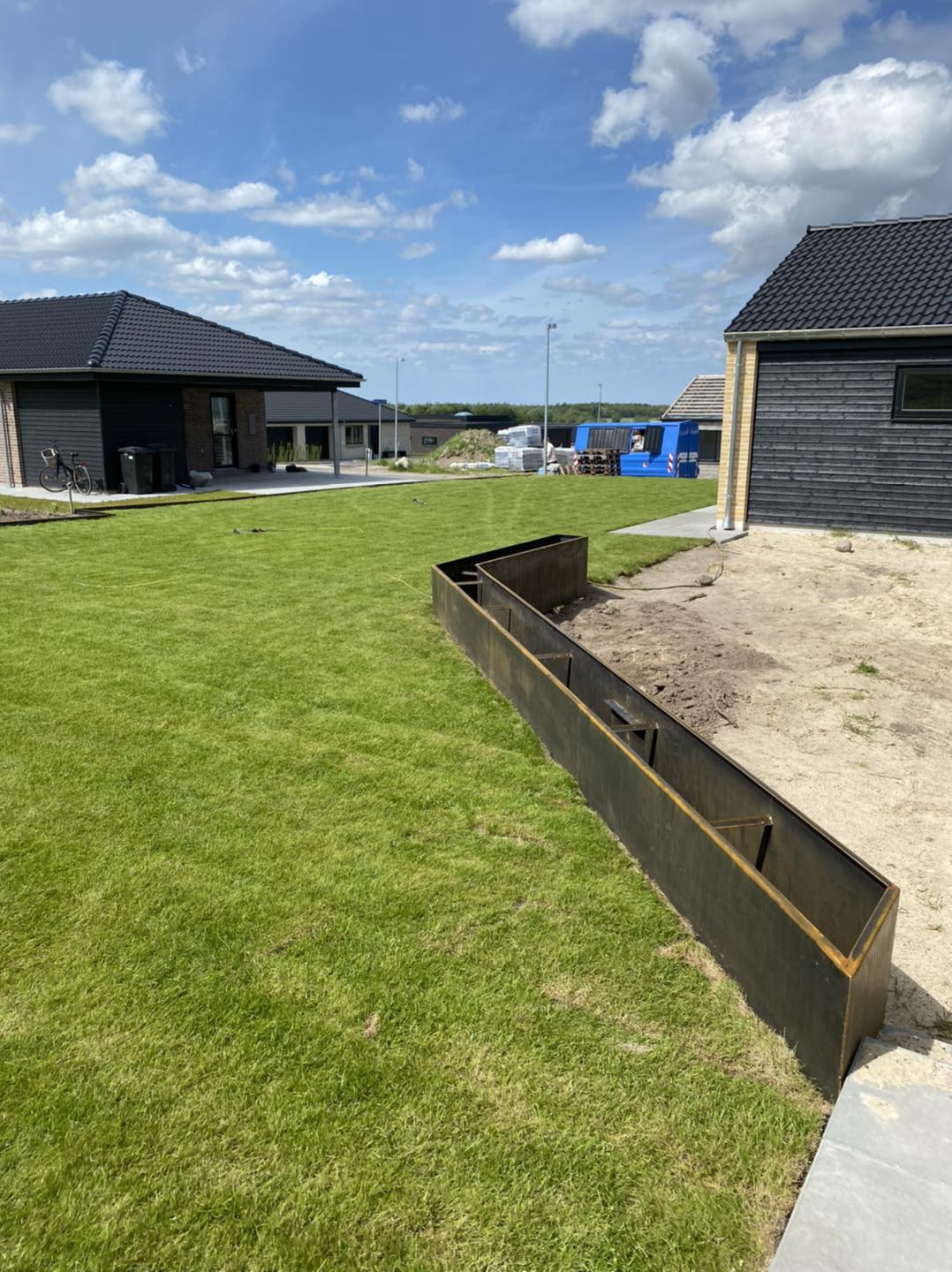 Have med nyanlagt græs og stålkant ved hus