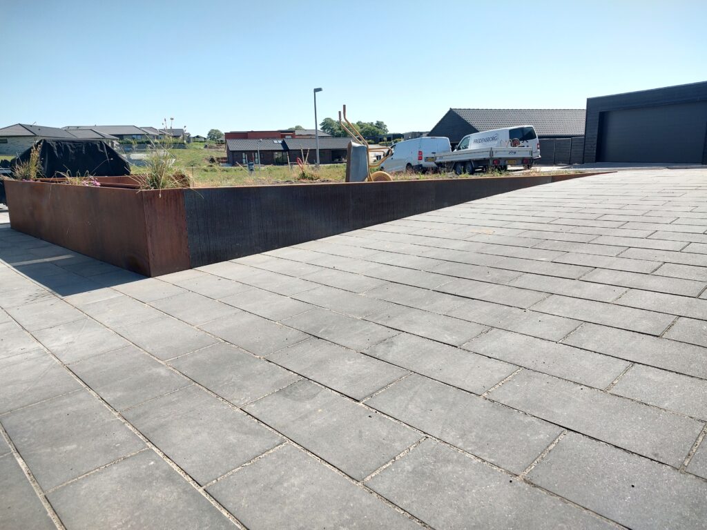 Ny flisebelægning ved moderne hus og havebed