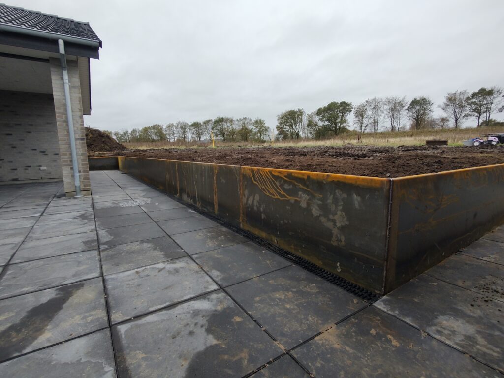 Hævet plantebed ved moderne hus med flisebelægning