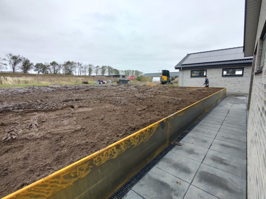 Haveanlæg og jordarbejde ved moderne hus med solceller